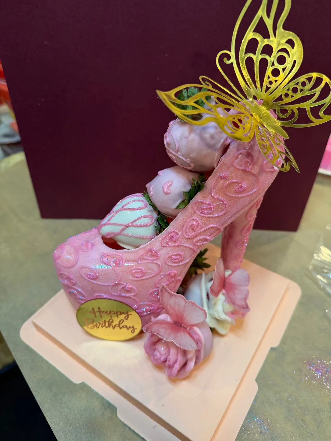 Pink chocolate high heel filled with strawberries and topped with a gold butterfly